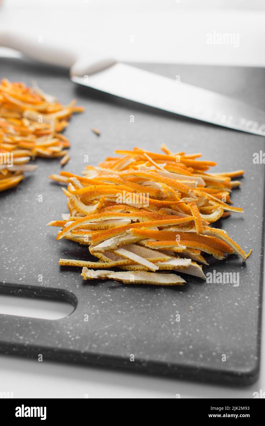 Scorza d'arancia tagliata a fette sottili, scorza d'arancia juliennata sul tagliere, buccia d'arancia Foto Stock