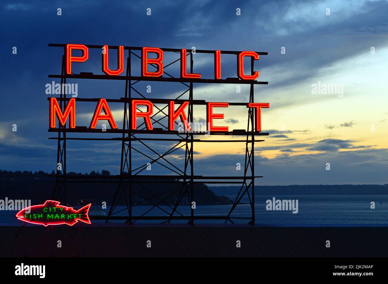 Il segnale al neon per il mercato pubblico di Seattle è illuminato al crepuscolo sulle rive del Puget Sound Foto Stock