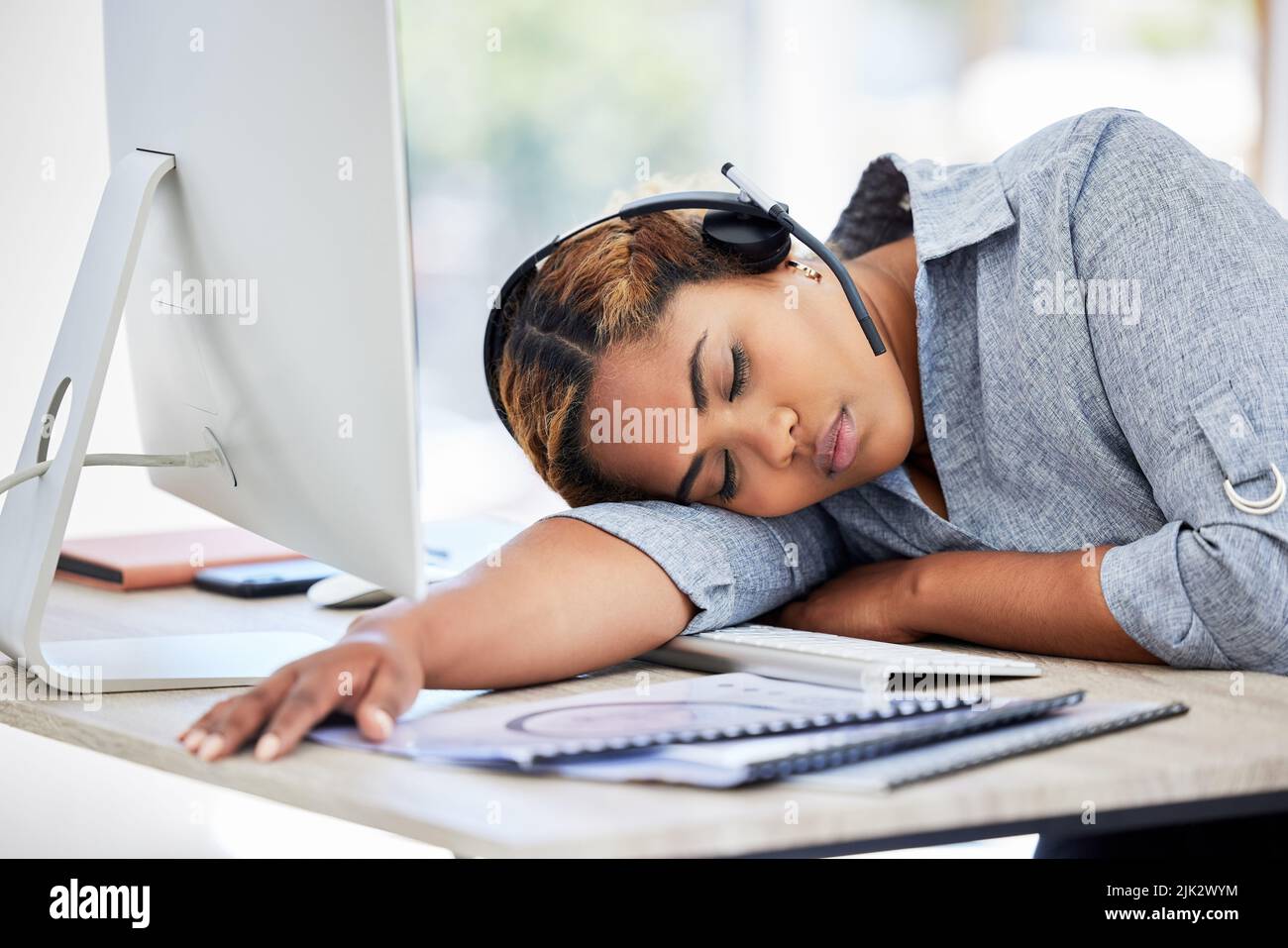 Agente del call center stanco e addormentato in ufficio nel pomeriggio. Giovani donne d'affari esauste che riposano sulla scrivania in un ufficio. Sensazione femminile Foto Stock