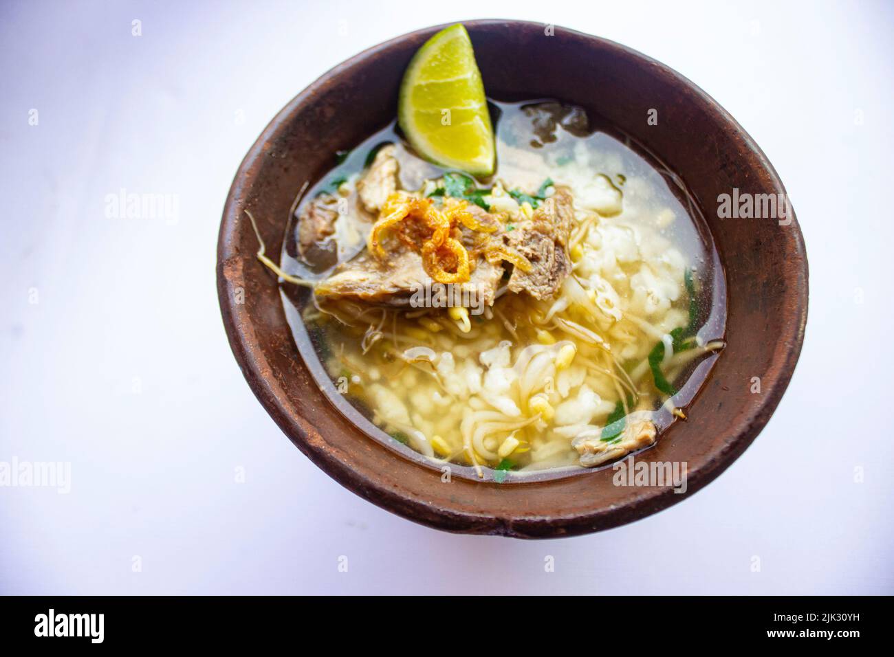 soto kwali. isolato su sfondo bianco. Zuppa di manzo giavanese limpida con germogli di manzo, lime e riso; servita in una ciotola tradizionale di kwali (un con Foto Stock