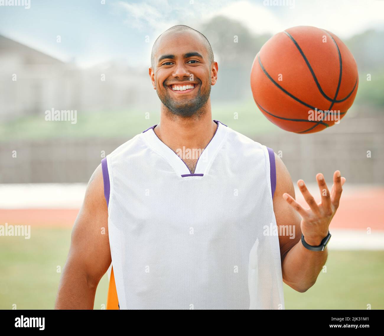 Su per un piccolo uno su uno. Ritratto corto di un bel giovane giocatore di basket maschile in piedi fuori con una basket in mano. Foto Stock