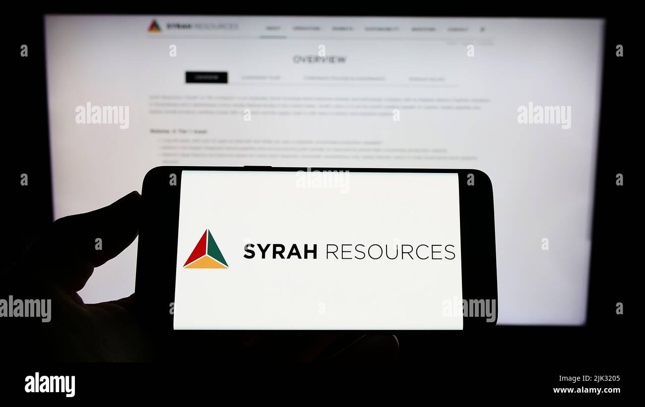 Persona che tiene lo smartphone con il logo della società australiana Syrah Resources Limited sullo schermo di fronte al sito web. Mettere a fuoco sul display del telefono. Foto Stock