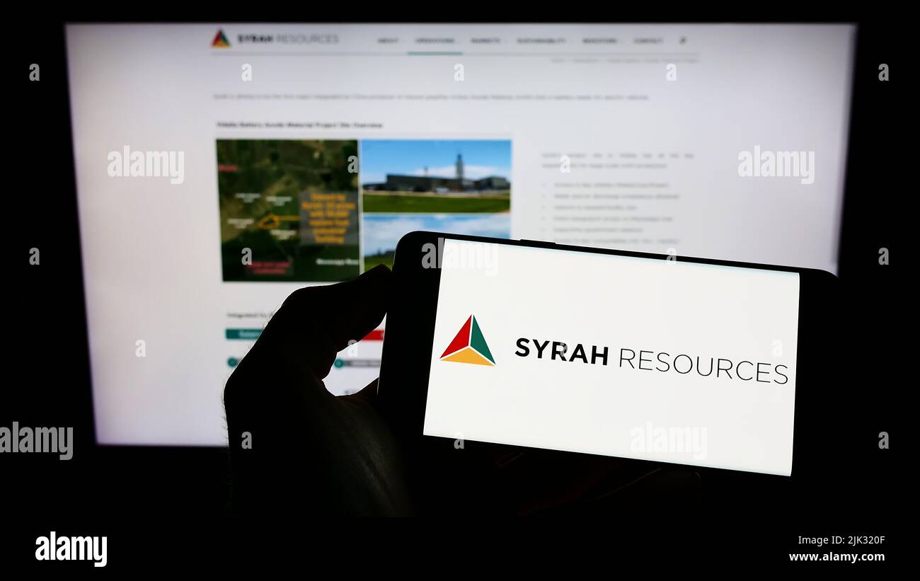 Persona che tiene il cellulare con il logo della società australiana Syrah Resources Limited sullo schermo di fronte al sito web aziendale. Mettere a fuoco sul display del telefono. Foto Stock