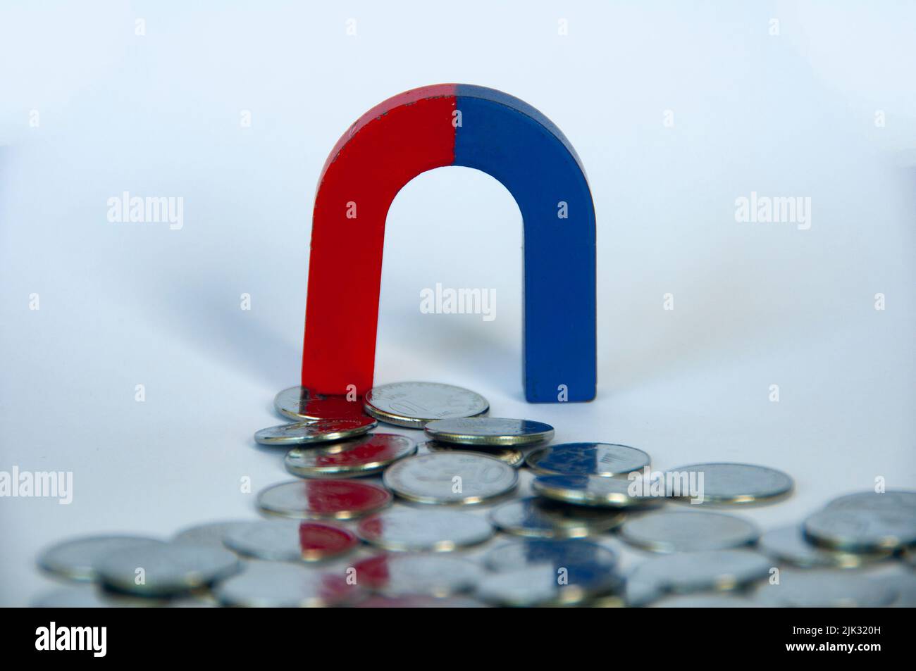 Magnete che attrae monete d'argento con fondo bianco. Concetto di business e legge dell'attrazione Foto Stock