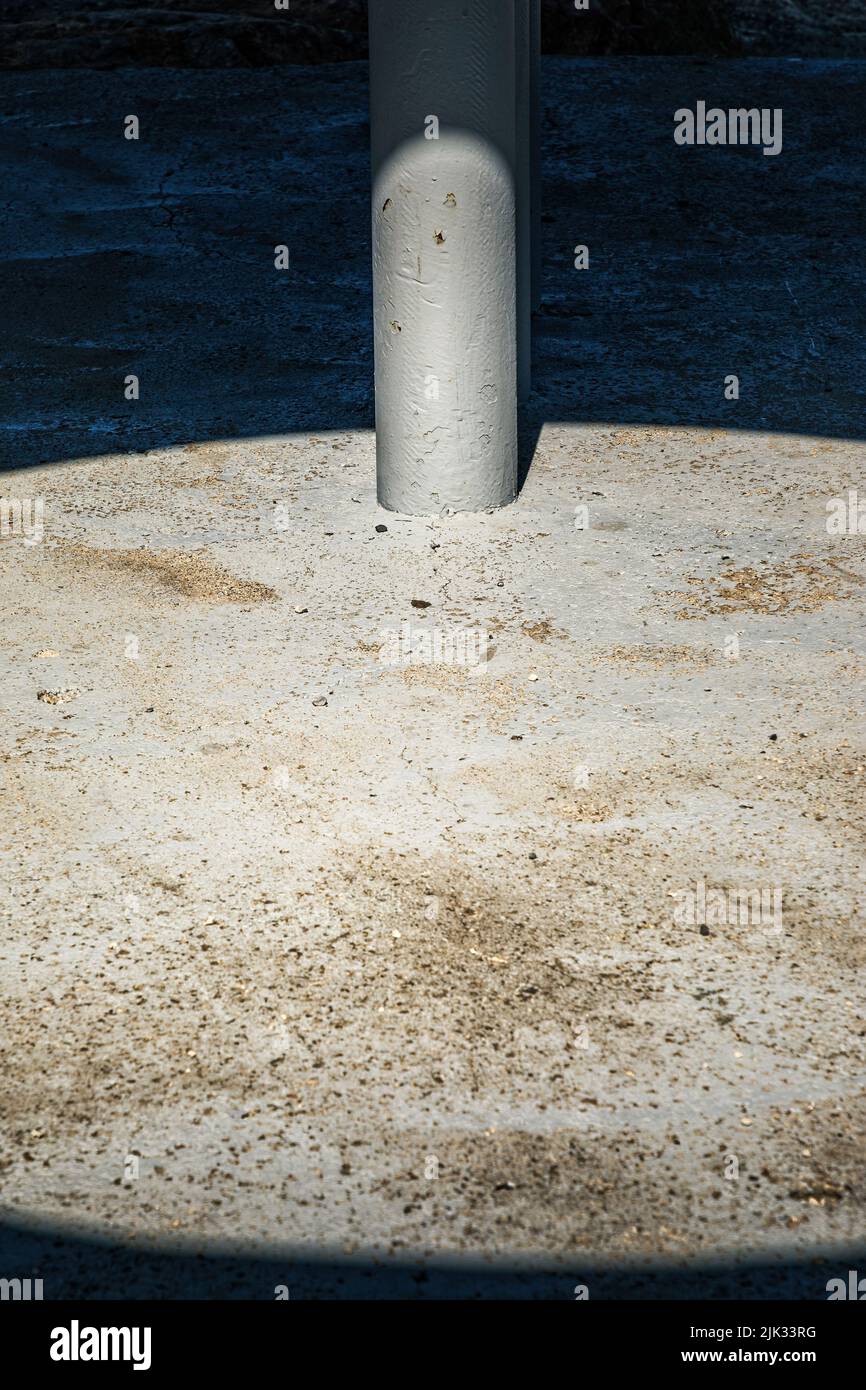 Palo in un anello di cemento con luce dura e ombra, spazio copia Foto Stock