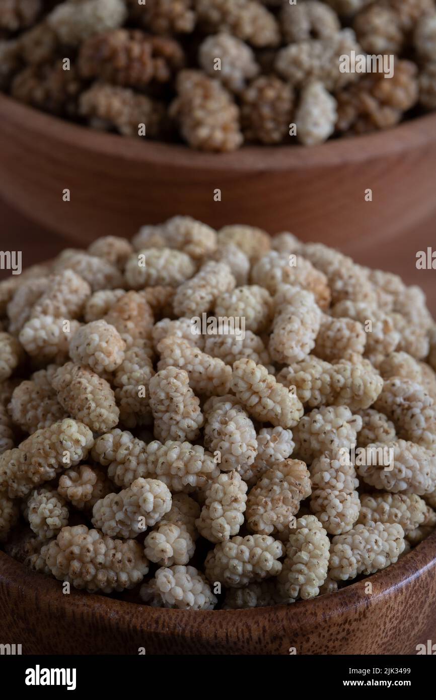 Ciotola piena di gelso secco su sfondo di legno Foto Stock