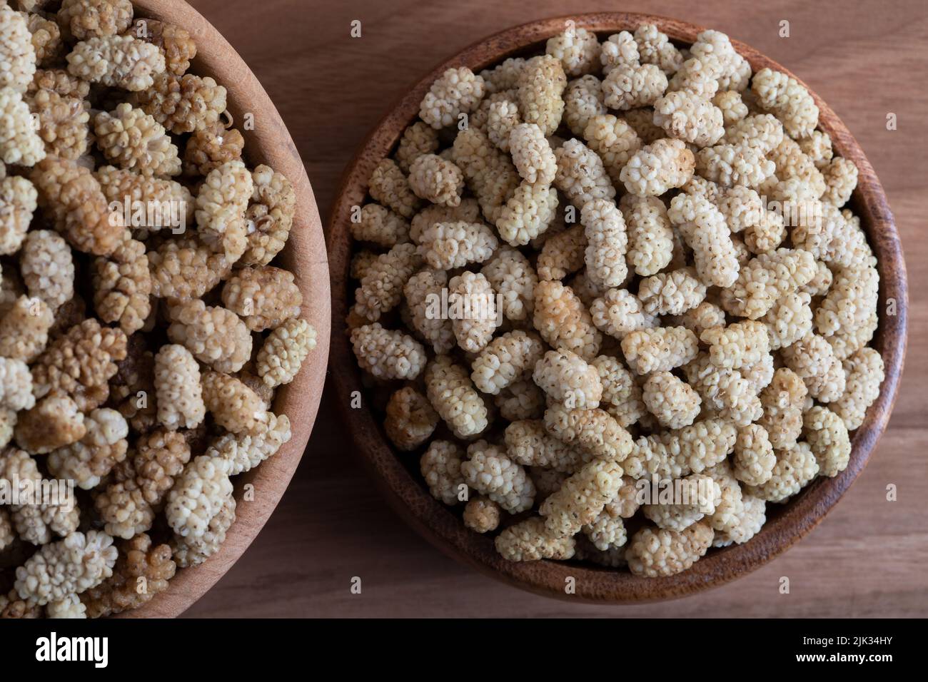 Ciotola piena di gelso secco su sfondo di legno Foto Stock