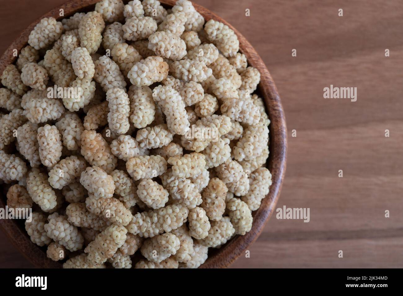 Ciotola piena di gelso secco su sfondo di legno Foto Stock