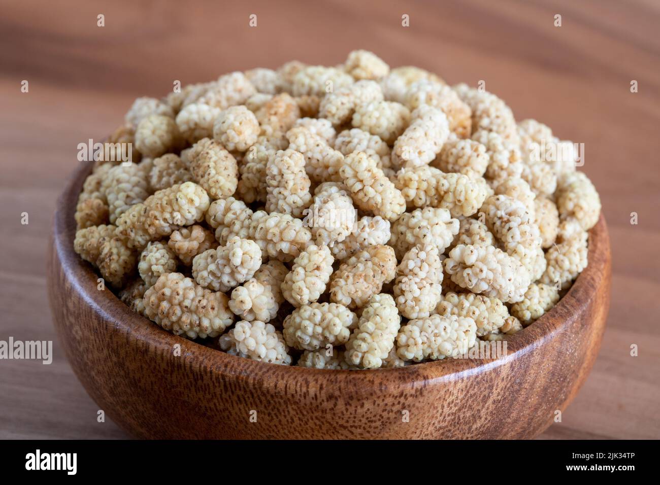 Ciotola piena di gelso secco su sfondo di legno Foto Stock