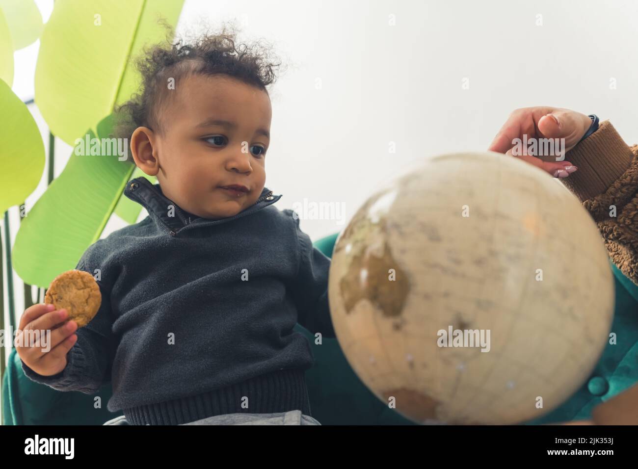 Il piccolo cucito africano americano è vicino a sua madre che sta puntando al Globe - isolato. Foto di alta qualità Foto Stock