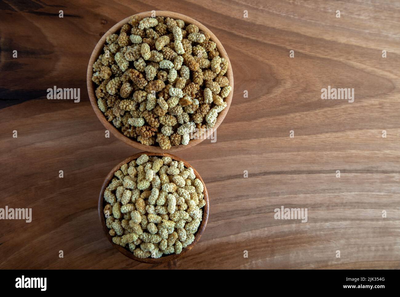 Ciotola piena di gelso secco su sfondo di legno Foto Stock