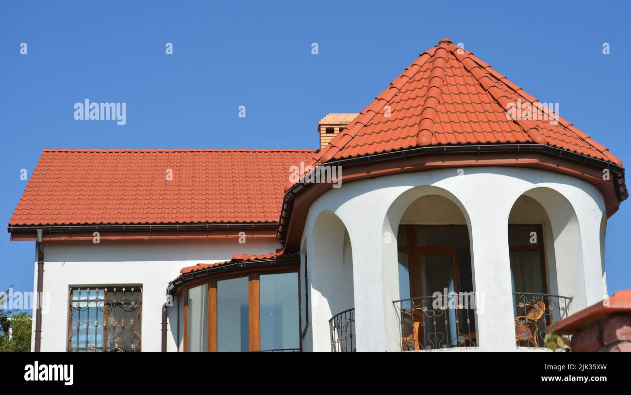 Una casa moderna con terracotta argilla, tetto piastrellato in ceramica, cerchio aperto balcone ad arco con ringhiera in ferro battuto e raggio, sistema di grondaia del tetto curvo. Foto Stock
