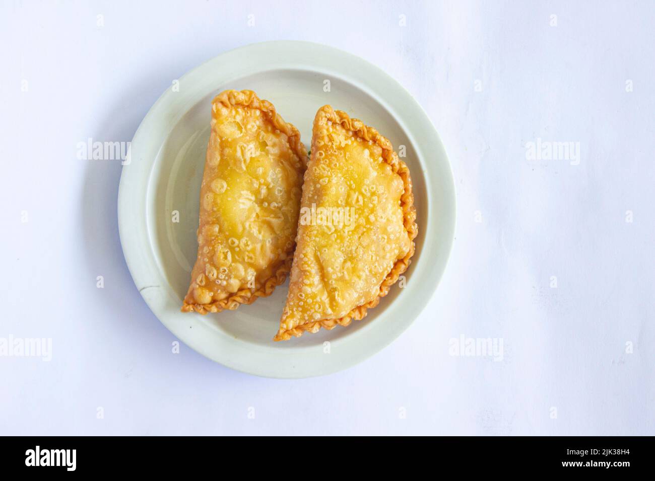 torta di pastie o torta di pasticceria o pastello kue servito con peperoncino verde in un piccolo piatto su sfondo di legno. torta pastello indonesiana Foto Stock