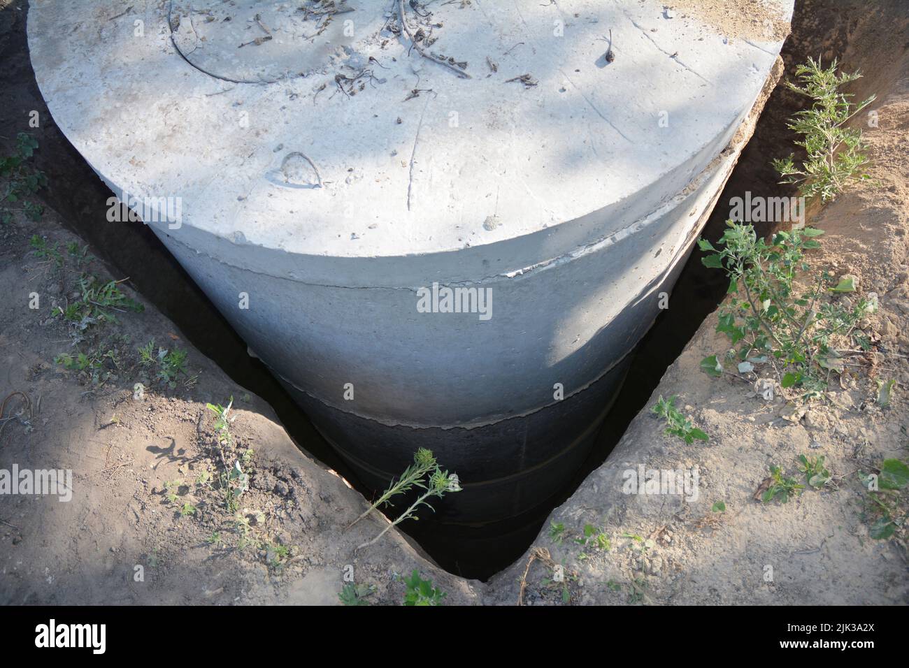 Installazione di un serbatoio settico in anelli di calcestruzzo. Pozzo di fognatura di calcestruzzo, installazione di anelli di botola in un foro quadrato. Foto Stock