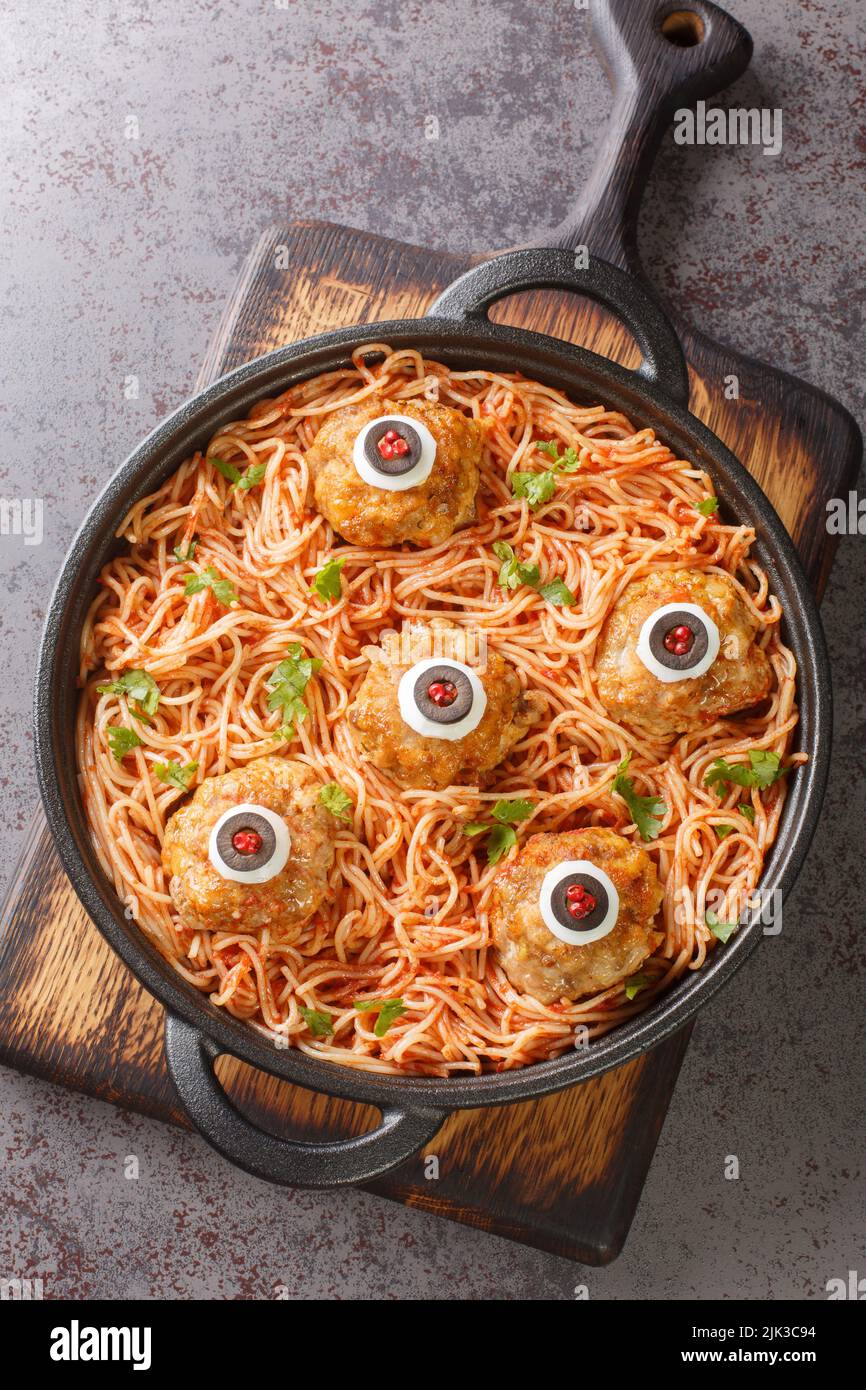 Pasta decorata con polpette occhi primo piano nel piatto sul tavolo Menu su Halloween. Vista dall'alto verticale Foto Stock