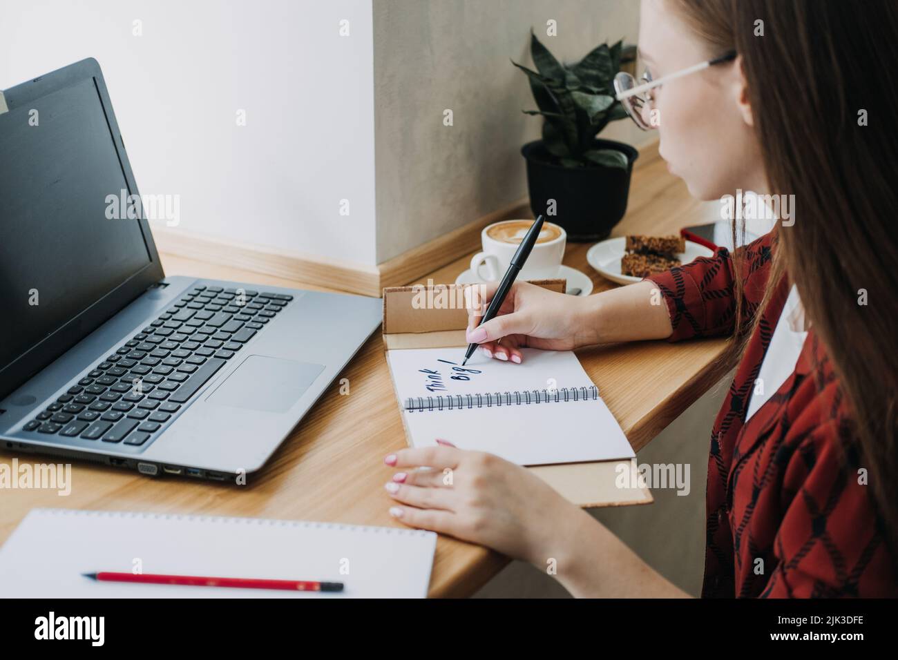 Il lavoratore o la scrittura della donna dello studente pensano la frase motivazionale grande nel taccuino aperto Foto Stock