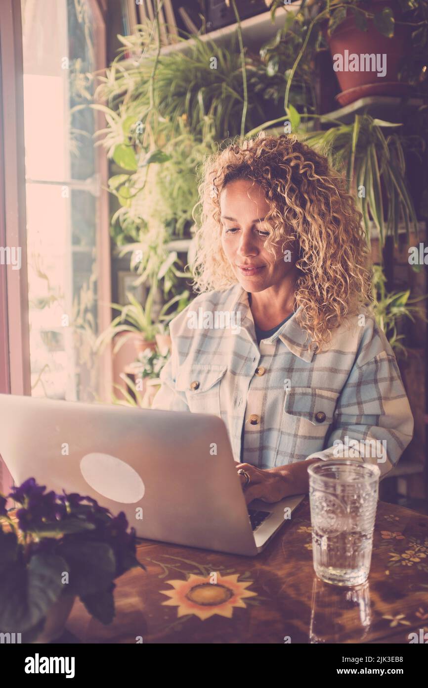 Concetto di persone che lavorano online con un notebook in un ambiente di lavoro domestico alternativo. Giovane donna godere e gestire il suo web business internet con un compu Foto Stock
