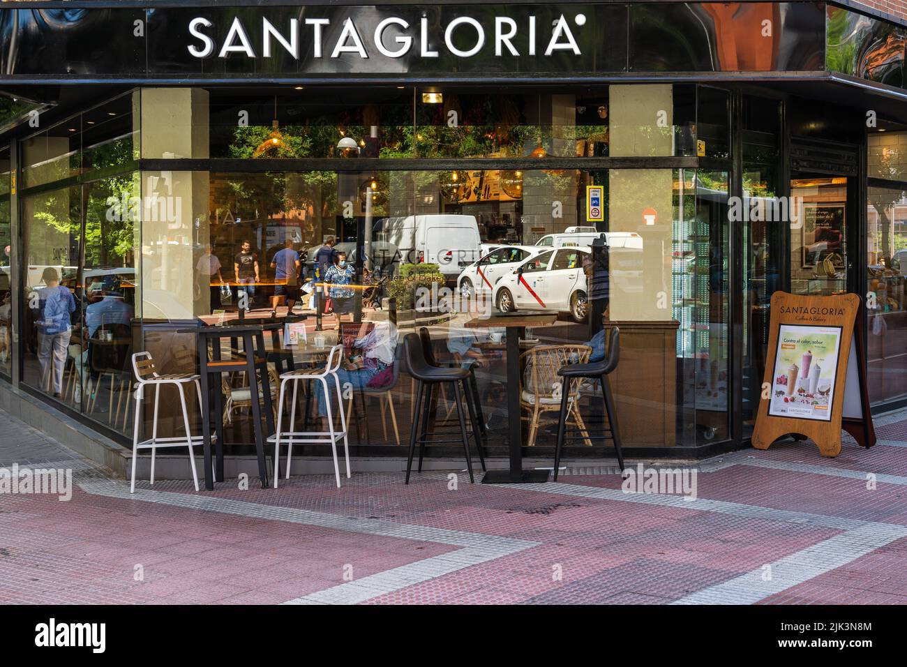 Madrid, Spagna -- 24 giugno 2022 -- Foto di un ristorante d'angolo a Madrid con traffico stradale riflesso nelle vedove. Foto Stock