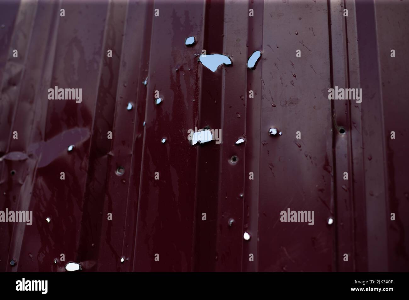 Recinzione vicino alla casa con buchi proiettili e carapelli dopo colpi di arma da fuoco e combattimenti durante l'invasione delle truppe russe in Ucraina Foto Stock