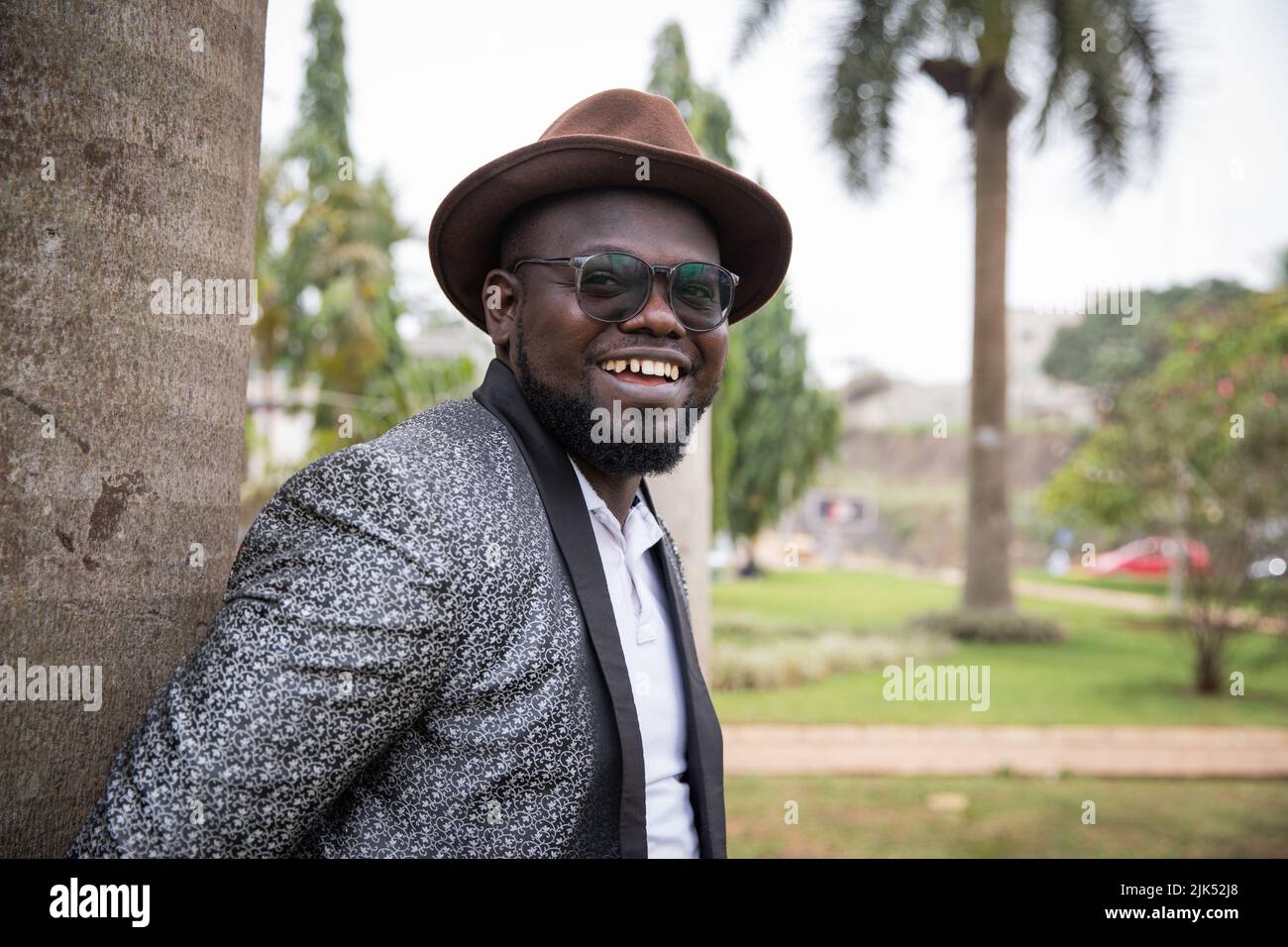 L'elegante uomo d'affari africano sembra sorridente nel parco. Concetto all'aperto. Foto Stock