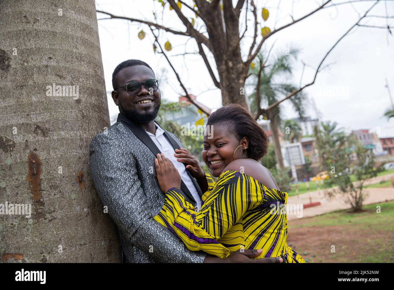 Attraente giovane coppia nera abbracciata nel parco sorride a quelli di fronte a loro. Foto Stock