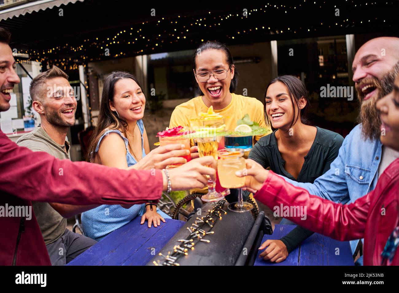 Divertente gruppo multiculturale di amici che si godono drink serali al Bar. Persone che si divertono insieme Foto Stock