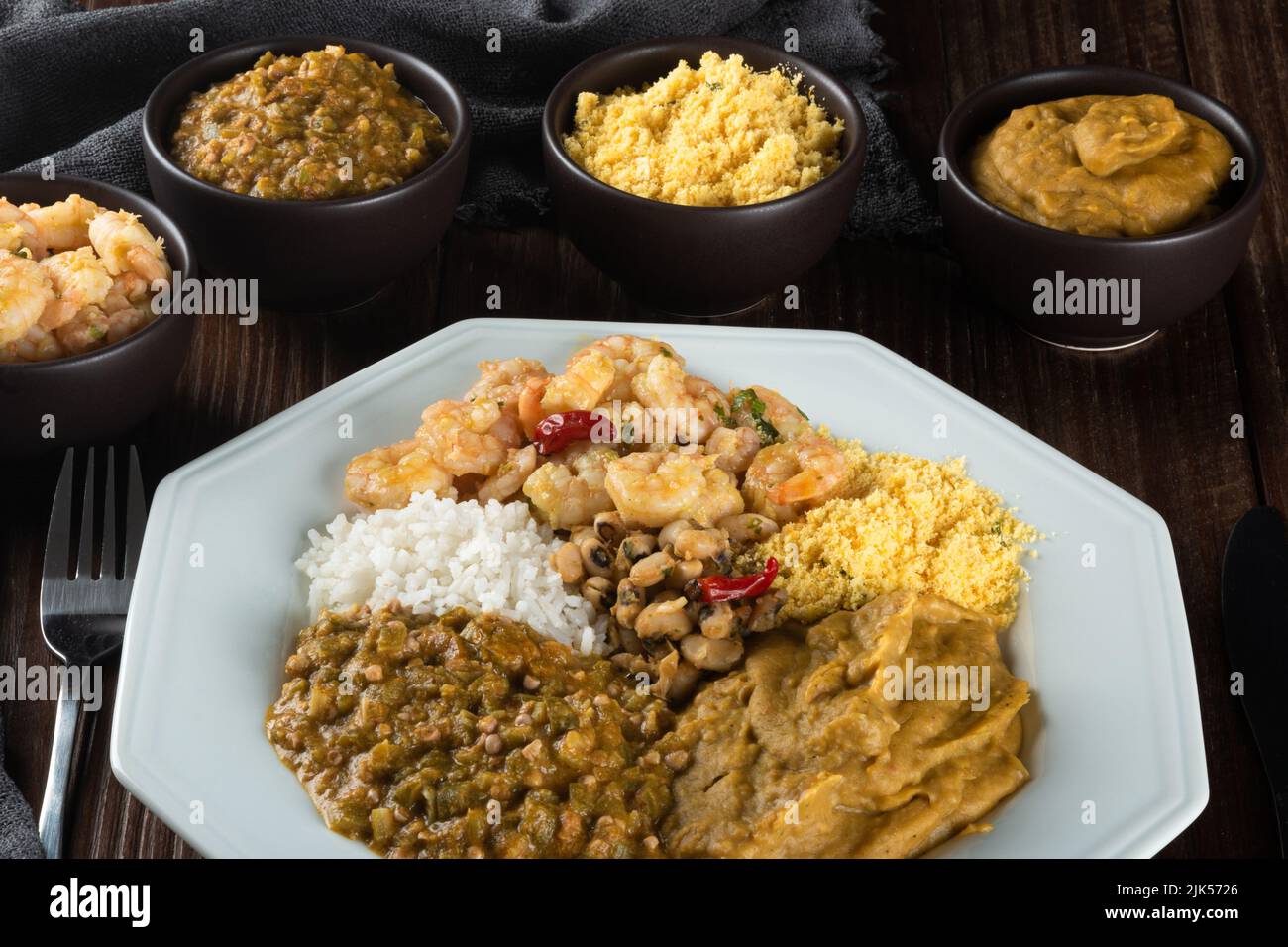 Caruru. Piatto tradizionale afro-brasiliano a base di okra e gamberetti secchi, accompagnato da vatapa, fagioli, riso, gamberetti e farofa Foto Stock