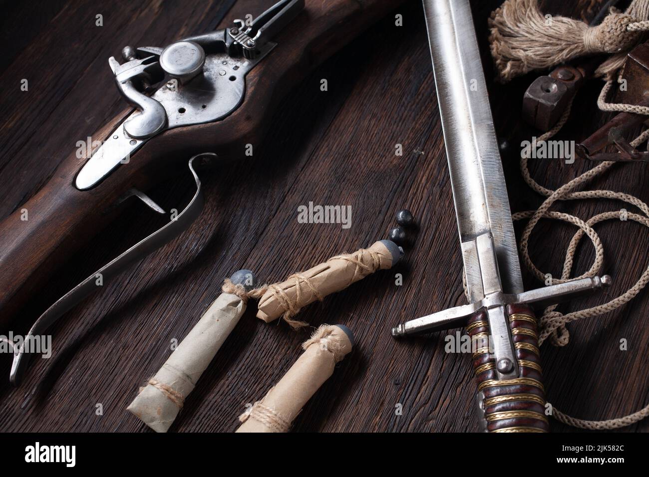antico muschio di flintlock del xvii secolo con fiasca di polvere e pallottole a led su ponte di legno. Foto Stock