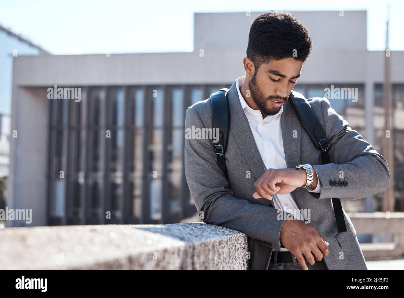 Quanto tempo devo aspettare, un giovane uomo d'affari che controlla il tempo in città. Foto Stock