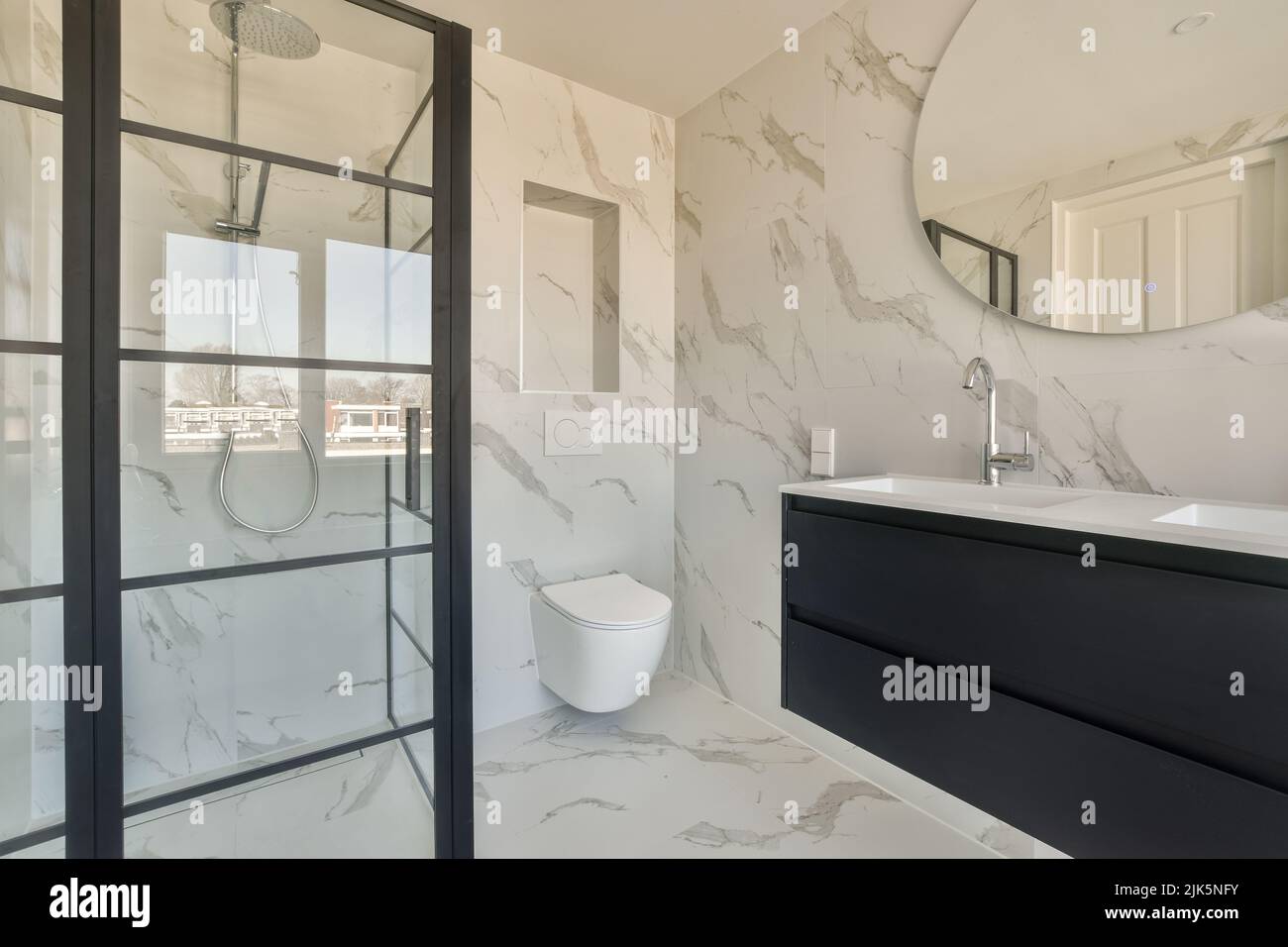 Spazioso bagno con lavandino in pietra bianca e cabina doccia in un costoso appartamento di colore nero Foto Stock