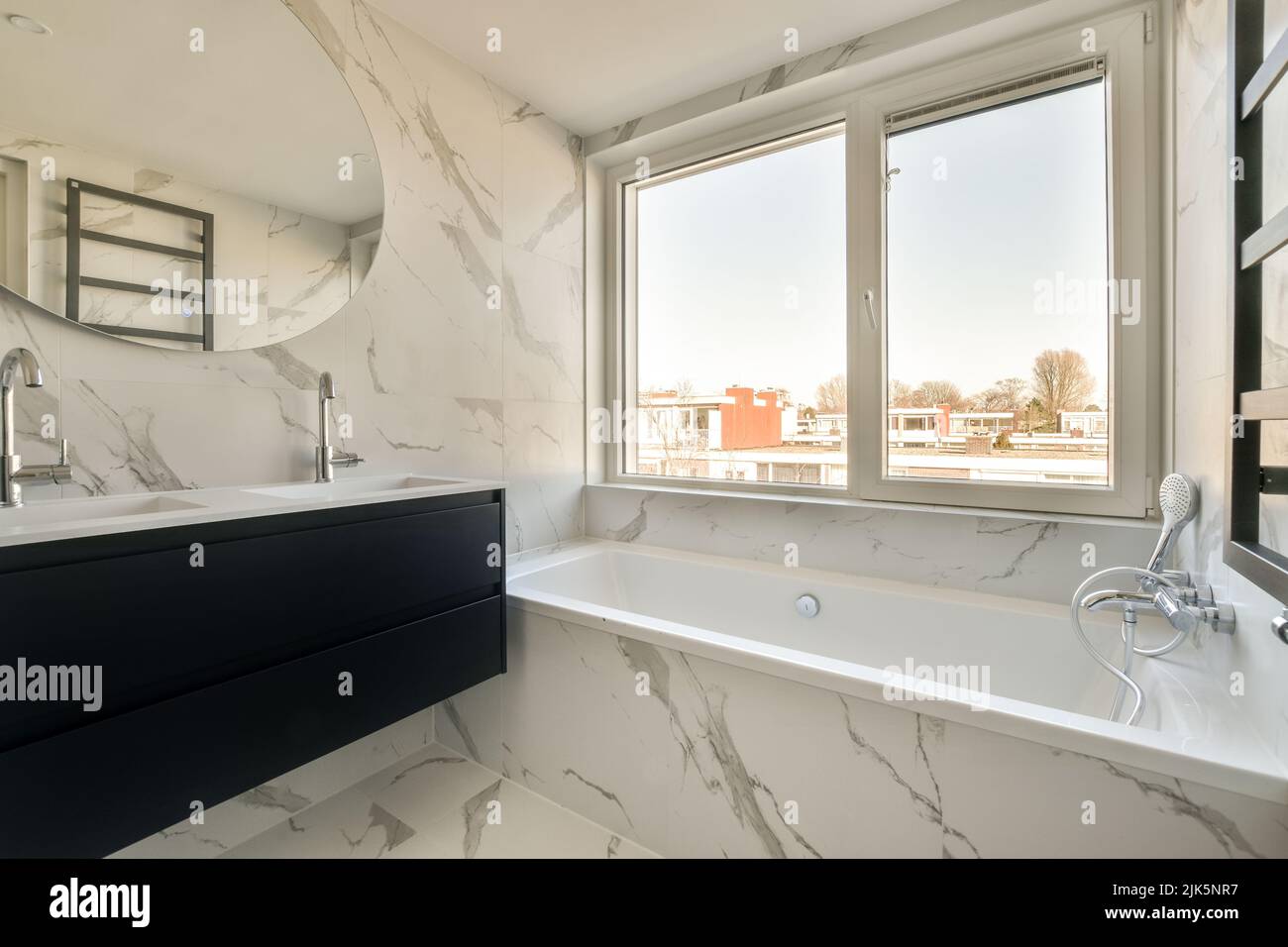 Spazioso bagno con lavandino in pietra bianca e cabina doccia in un costoso appartamento di colore nero Foto Stock