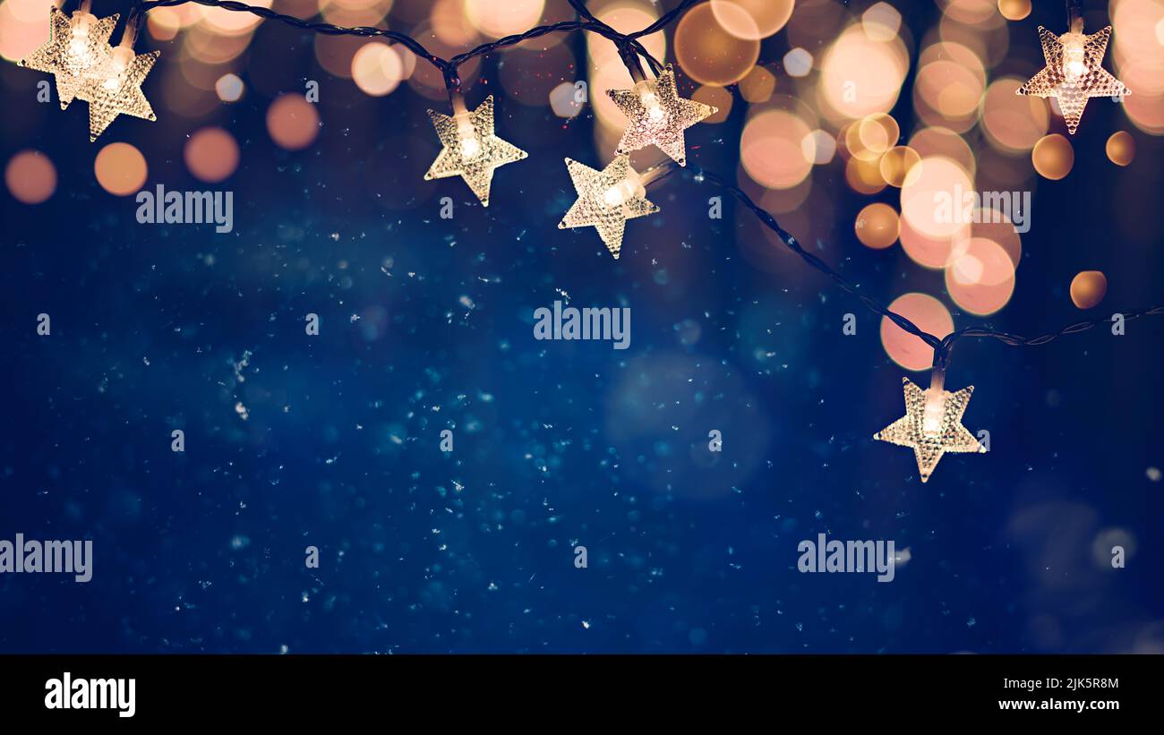 Luci a forma di stella a forma di stringa di Natale su sfondo blu notte con luci dorate bokeh Foto Stock