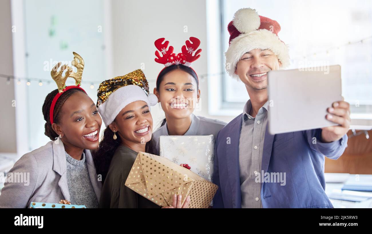 Festeggia il Natale con persone buone. Un gruppo di colleghi che si prende un selfie mentre festeggia il Natale al lavoro. Foto Stock