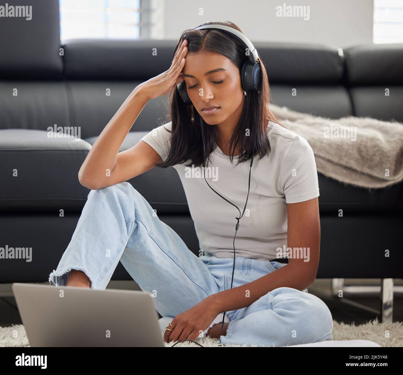 Non capisco come funziona. Una giovane donna attraente che indossa le cuffie e si sente stressata durante l'uso del suo laptop. Foto Stock