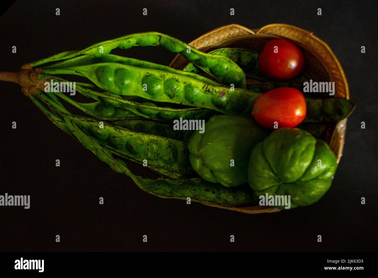 pomodori tropicali con jipang o labu siam o chayote e cipolla sono serviti in un cestino isolato su sfondo nero Foto Stock