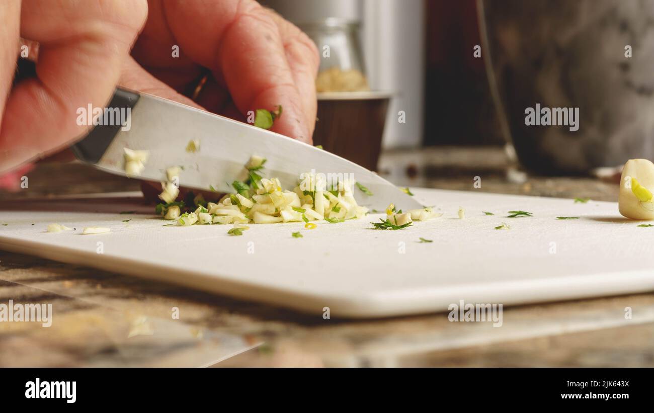 tritare l'aglio e il prezzemolo con un coltello Foto Stock