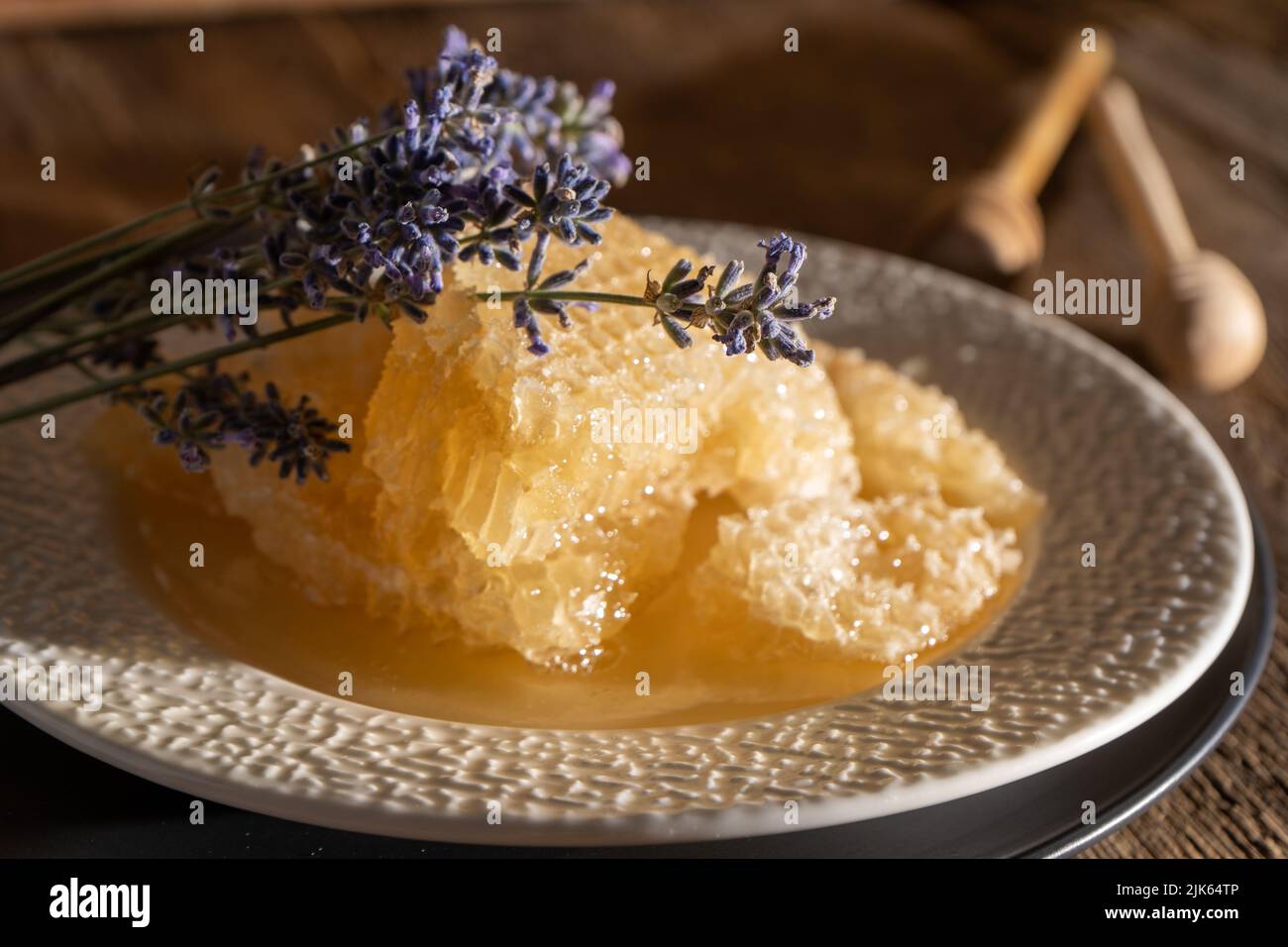 Miele e nido d'ape su un piatto bianco. Cibo dolce in una ciotola sul tavolo. Un prodotto dell'apicoltura. Fiore di lavanda. Foto Stock