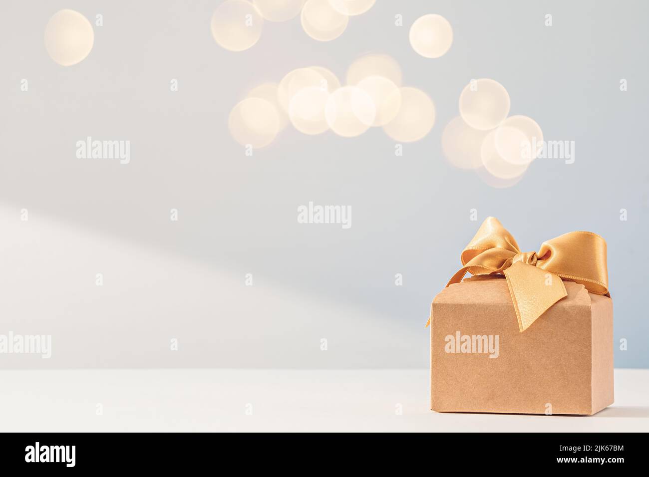 Confezione regalo in carta Kraft con arco in nastro d'oro su bianco Foto Stock