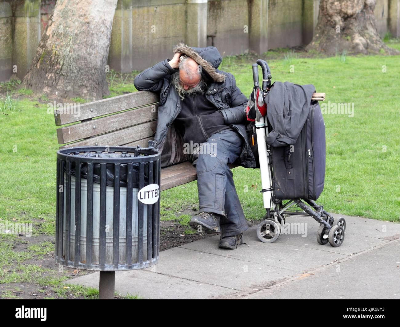 Londra, Regno Unito - Mar 21, 2021: Uomo senza tetto che dorme su una panchina nel parco Foto Stock