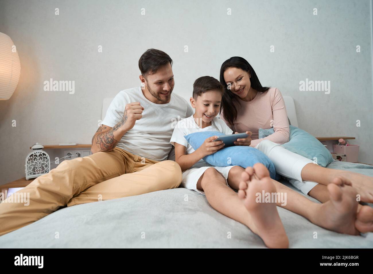 Papà, mamma e bambino trascorrono del tempo insieme guardando le foto al telefono Foto Stock