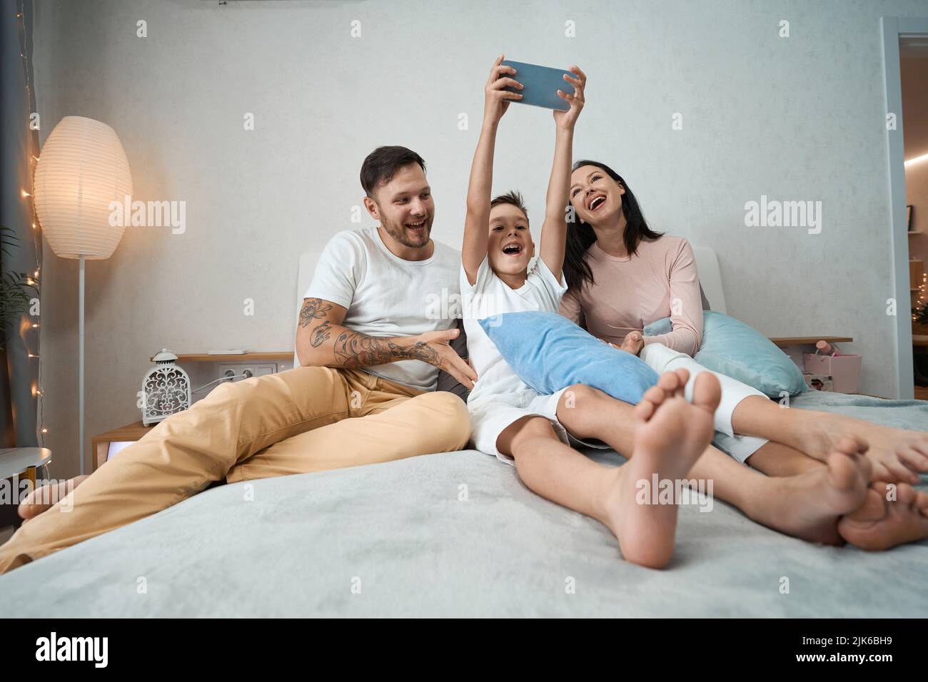 Il figlio adolescente prende selfie di famiglia nella camera da letto del genitore Foto Stock