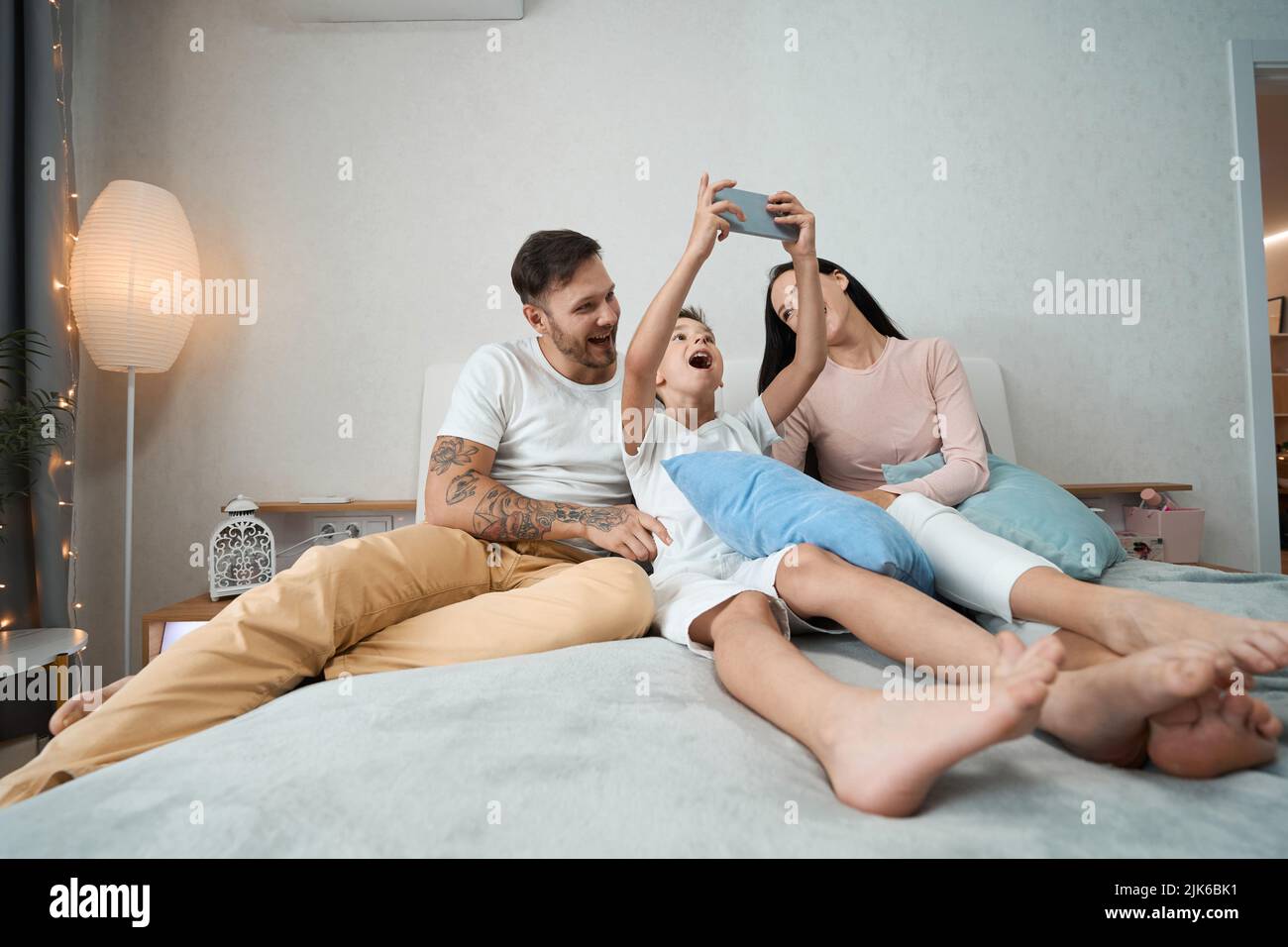 Famiglia selfie gioiosa famiglia di genitori e figlio in camera da letto casa Foto Stock