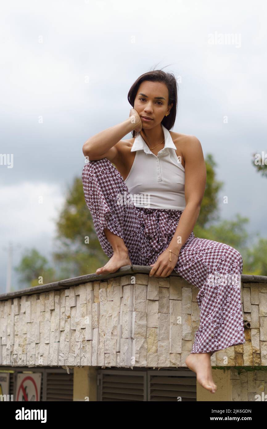 seduta fuori una giovane donna con capelli corti indossa abiti comodi ed e a piedi nudi stile di vita e bellezza Foto stock Alamy