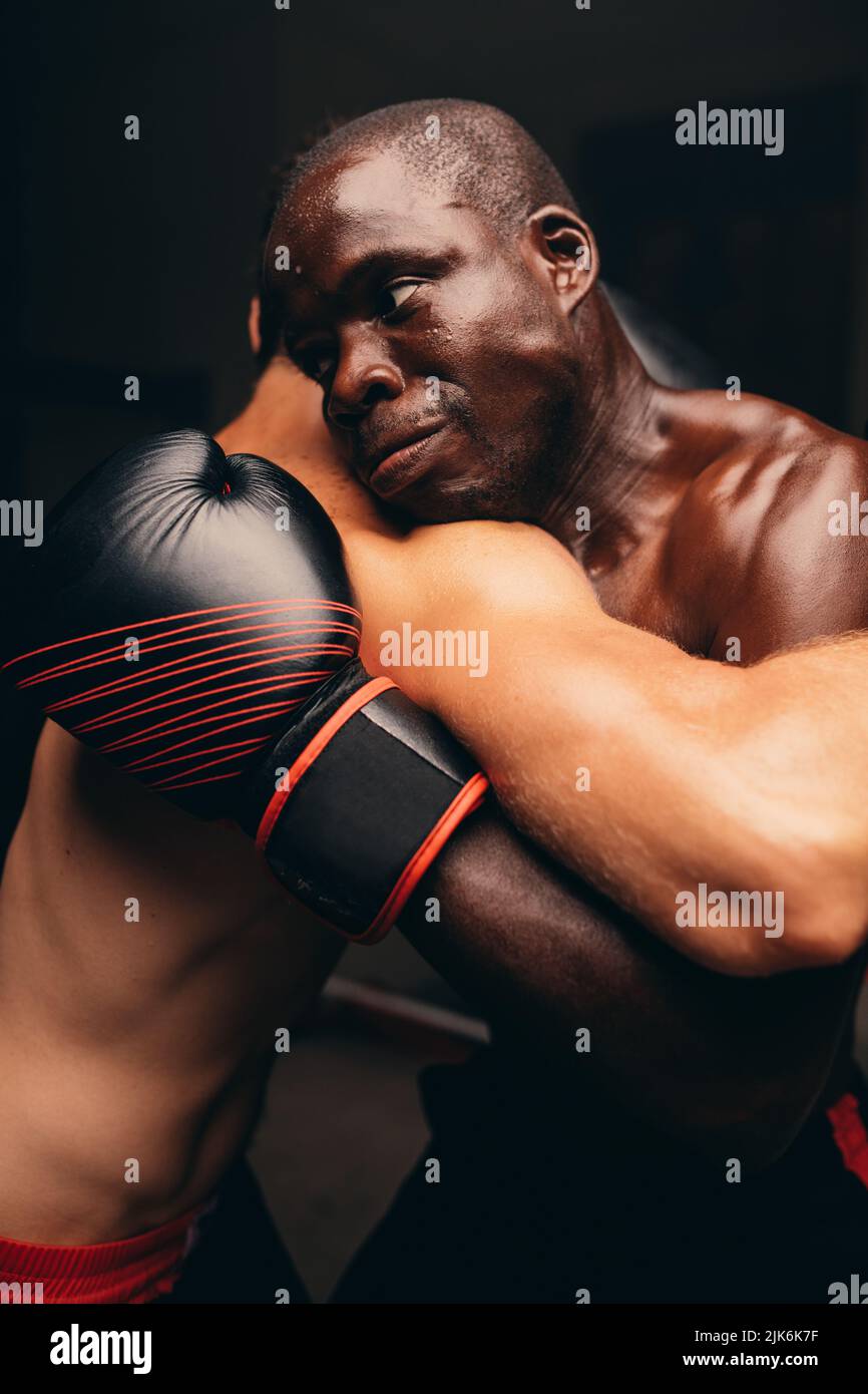 Due atleti maschi che combattono con guanti da boxe in palestra. Due giovani pugili che hanno una partita in un anello di boxe. Foto Stock