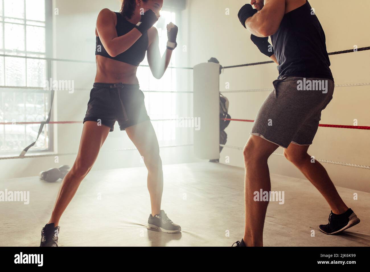 Due giovani lottatori che si affrontano senza guanti in un anello di pugilato. Due giovani pugili che si scatenano durante una sessione di allenamento in una palestra di boxe. Foto Stock