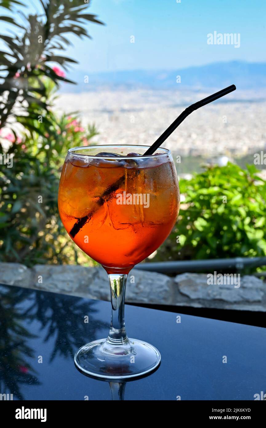 Grande bicchiere di Aperol Spritz drink con ghiaccio e una paglia in un bar di montagna. Nessuna gente. Foto Stock
