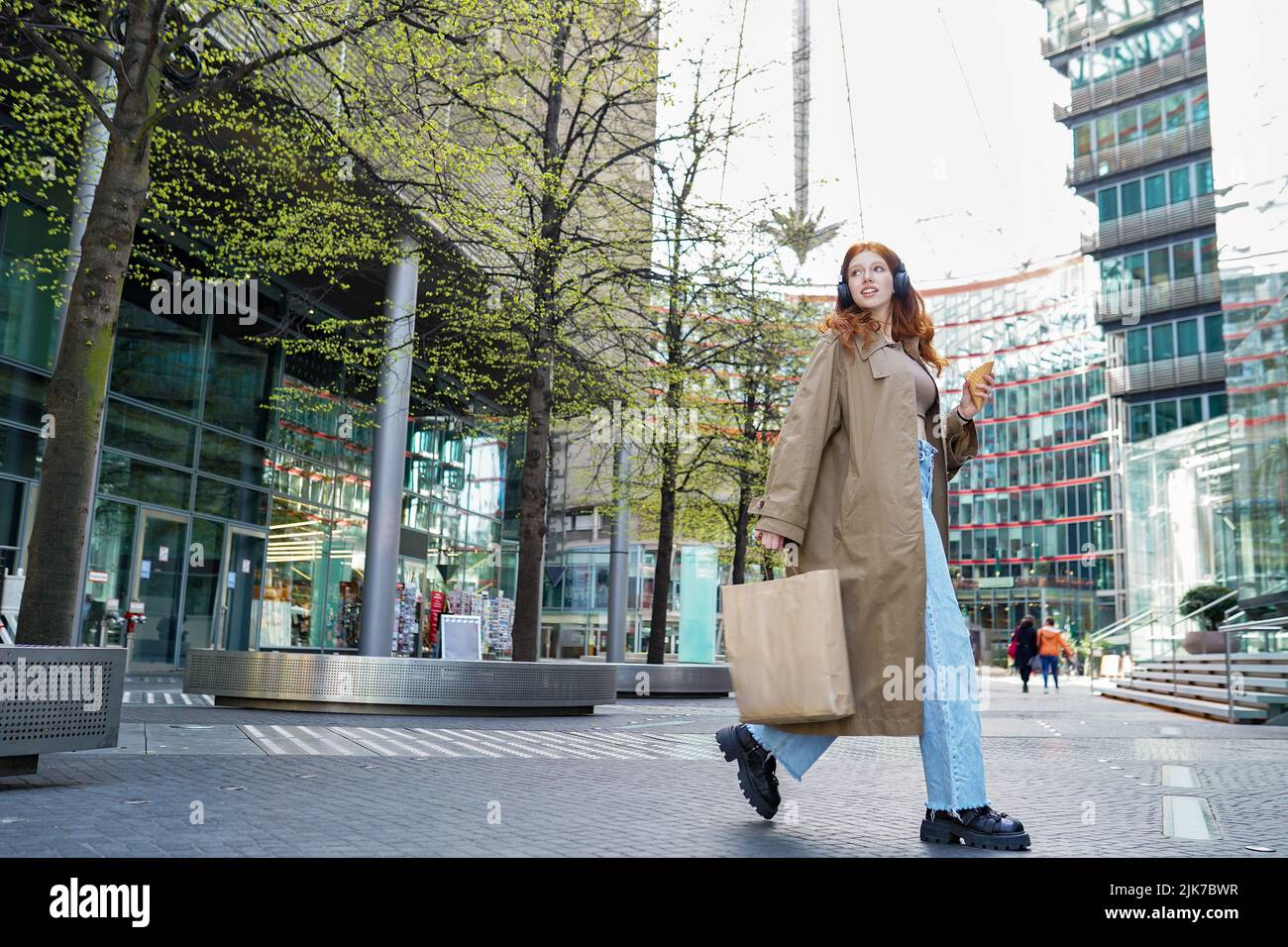 Moda ragazza modella cool che tiene borse shopping a piedi sulla strada trafficata grande città. Foto Stock