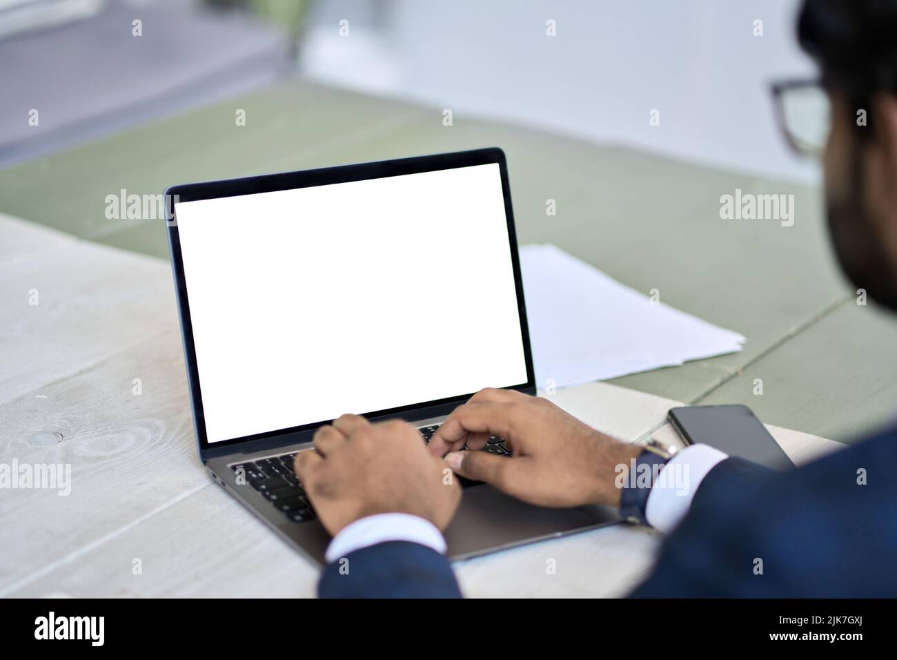 Uomo d'affari che indossa un abito da lavoro su un notebook con schermo bianco mock-up. Foto Stock