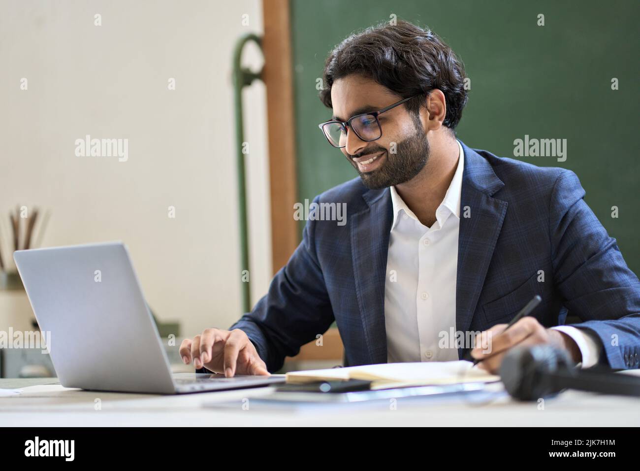 Felice arabo giovane uomo d'affari indiano che lavora guardando il webinar su un notebook. Foto Stock