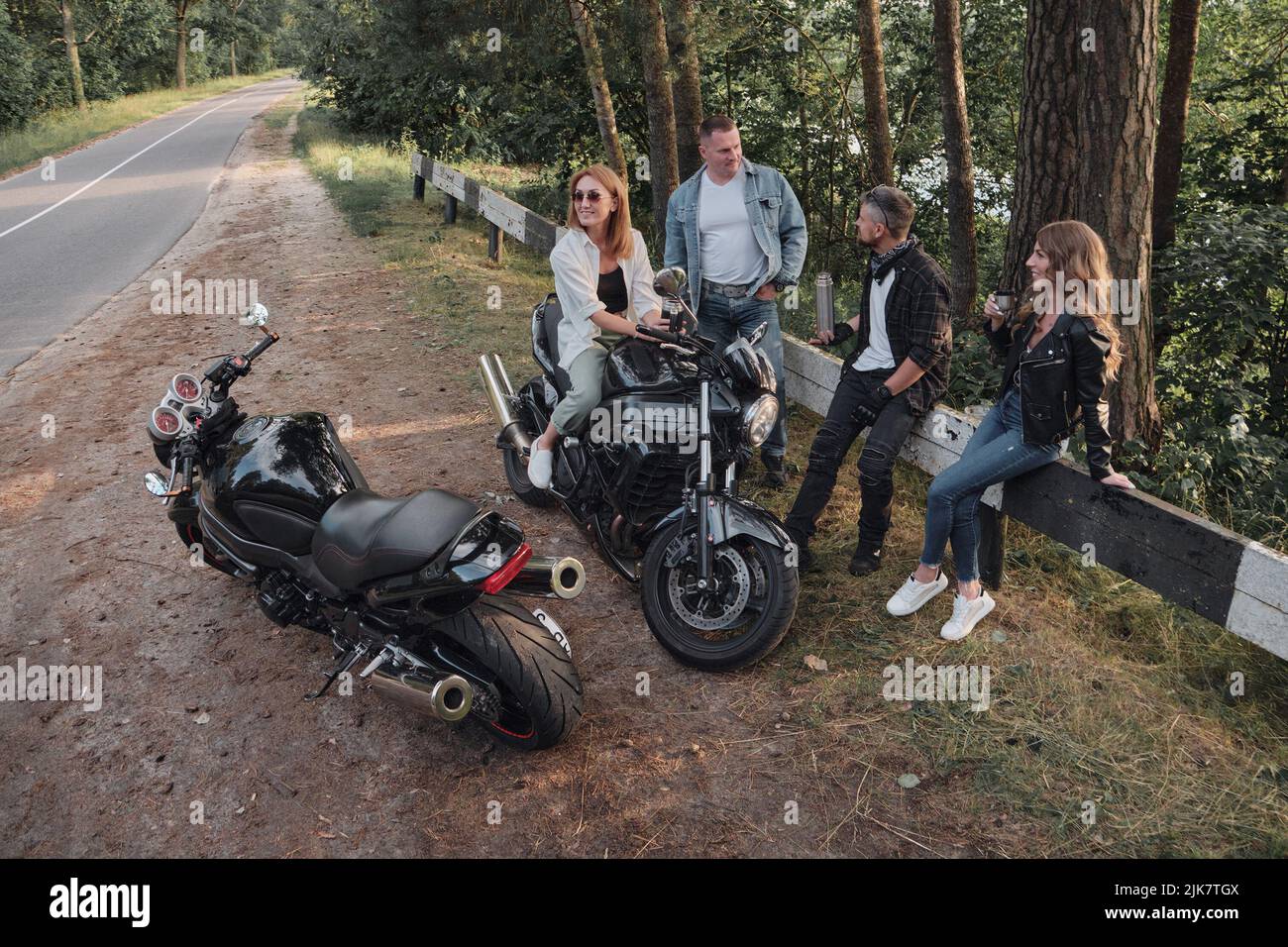 Incontrare Una compagnia di amici di motociclisti ciclisti ciclisti su moto si fermò sulla strada avendo divertimento e bevendo tè Foto Stock